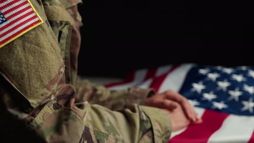 Military Person with Hands Resting on US Flag