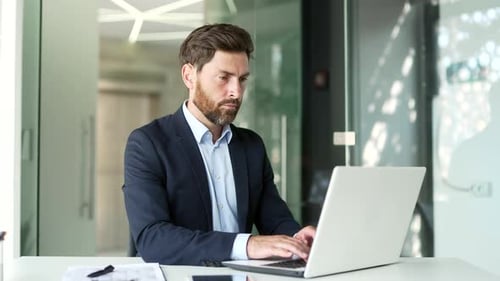 Busy businessman works on a laptop while sitting at workplace in business office.
