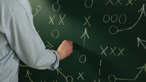 Man drawing American football game scheme on chalkboard, closeup