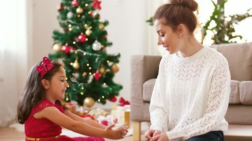 Girl Giving Christmas Present to Woman in Home
