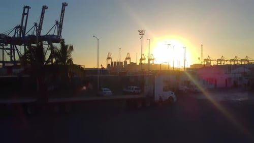 Sonnenuntergang in einem mexikanischen Zollhafen. Im Hintergrund sind Kräne und Schiffe zu sehen.