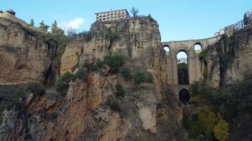 Landmark arch bridge of Ronda city with buildings on top of cliff, aerial view