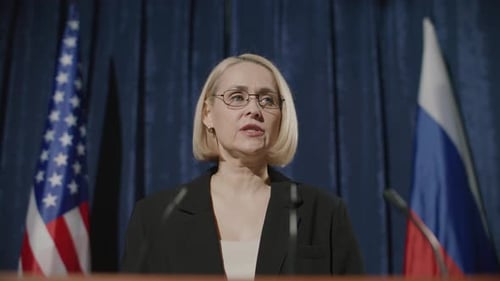 Woman Speaks at Press Conference with Flags