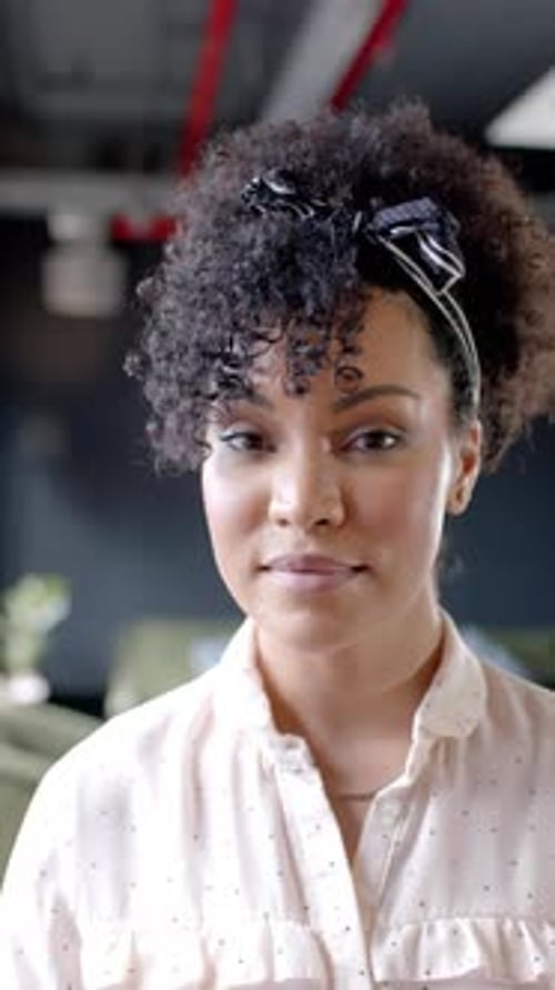 Vertical video of portrait of smiling african american businesswoman in office with copy space