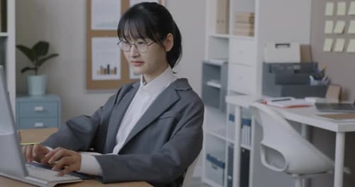 Slow Motion of Asian Businesswoman Working with Computer Sitting at Desk in Light Office