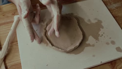 Close-up of Hands of Unknown Potter Moulding Clay on Board at Wooden Desk