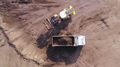 Excavator Fills Dump Truck with Dirt at Construction Site