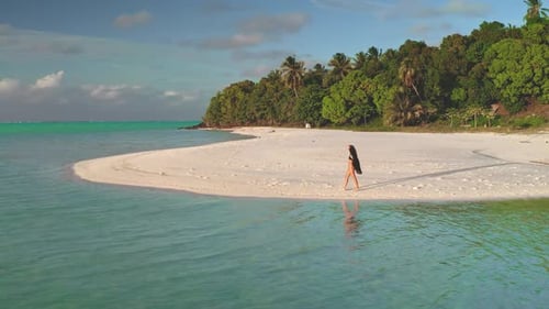 Young Woman Walking on a White Sand Beach in Tropical Paradise