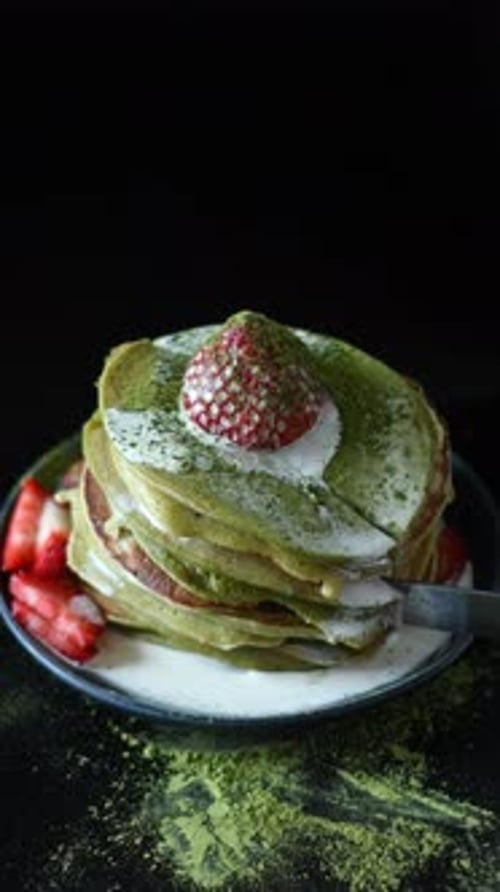 Green Pancakes with Strawberry Topping Being Cut