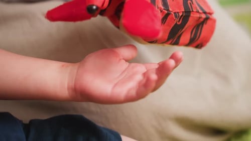 Nahaufnahme der Marionette, die beim Spielen im Klassenzimmer die Hand eines Kleinkindes berührt
