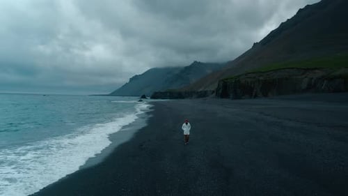 Man Walk on Empty Moody Black Sand Beach