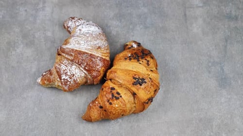 Two Croissants Rotating on a Gray Background Top View