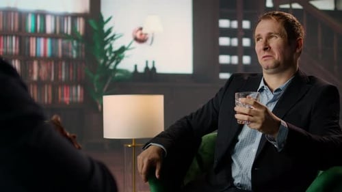 Man in Suit Holding Whiskey Glass Talking