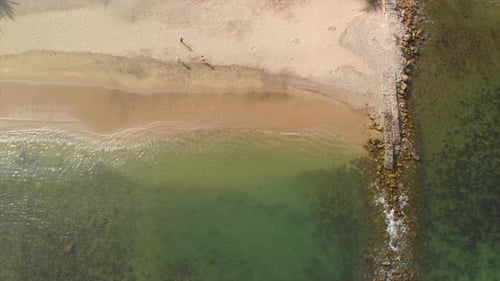 Aerial: People walking on the beach.