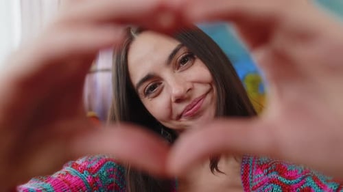 Woman Makes Heart Shape with Hands at Camera