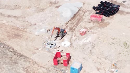 Vehículo excavador que prepara un conducto de tubería de concreto, vista aérea sobre la construcción de viviendas