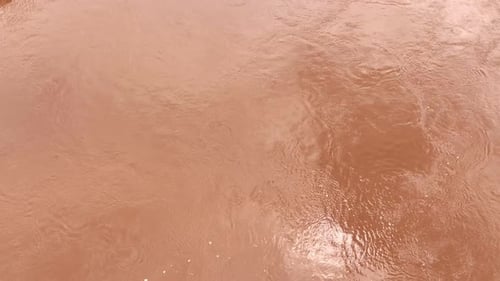 Overhead shot captures sediment-rich floodwaters in motion.