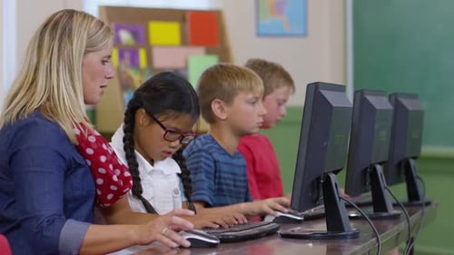 Teacher assists student with computer project in school classroom