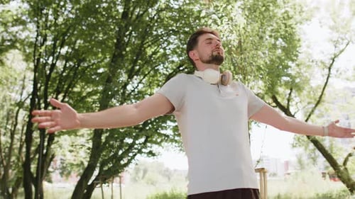 Man Stretching Arms in Sunny Urban Park
