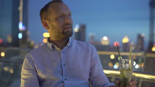 Portrait of Happy, Young Man Drinking Cocktail on Terrace in Bar At