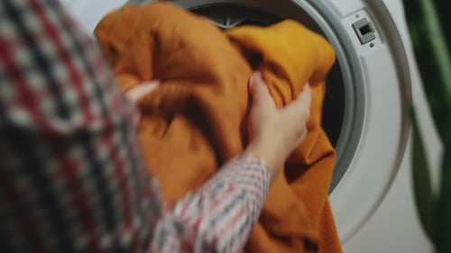 Person Loading Clothes Into Washing Machine