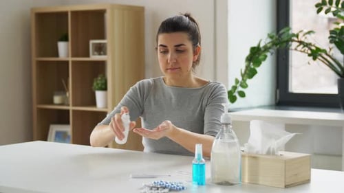 Woman sprays antibacterial sanitizer on hands at home for health and hygiene