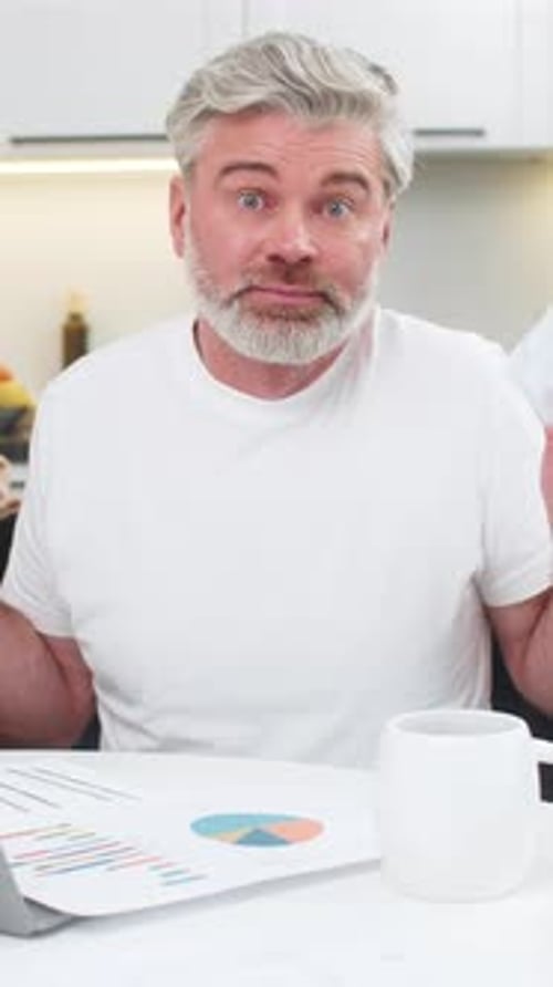 Man Looks at Financial Documents with Confused Expression