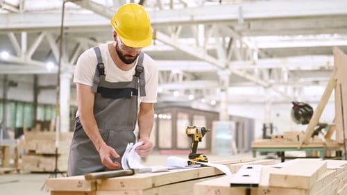 Un tas de documents papier et de plans. Ouvrier industriel dans un entrepôt en bois.