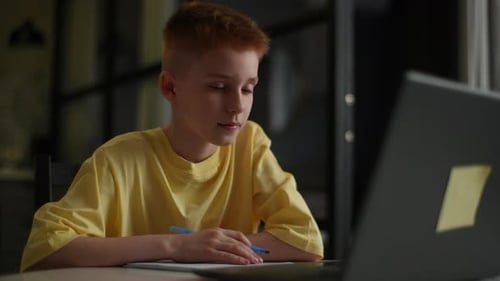 Boy Studying and Writing at Home With Laptop