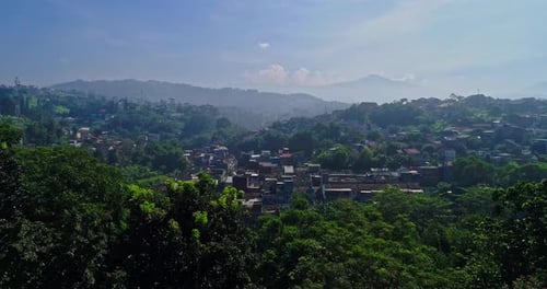 Aerial view of residential landscape amidst green trees and layers of hills