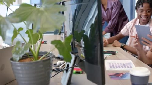 Collaborating on project, diverse team using tablet and laptop in modern office