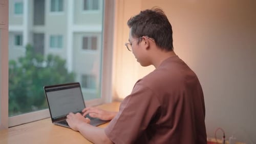 Konzentriertes Arbeiten Ein junger Mann ist konzentriert, während er auf seinem Laptop tippt.