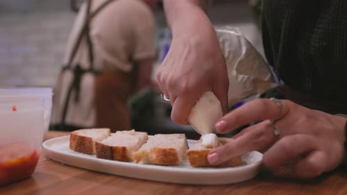 Hands Decorating Sliced Bread with White Cream