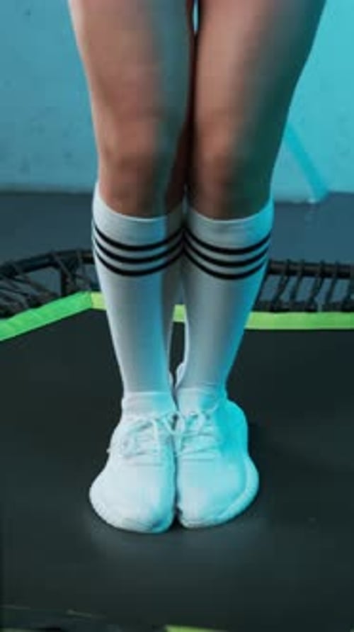 Close-up of legs of energetic young fitness girl in white sneakers who walks to mobile mini trampoli