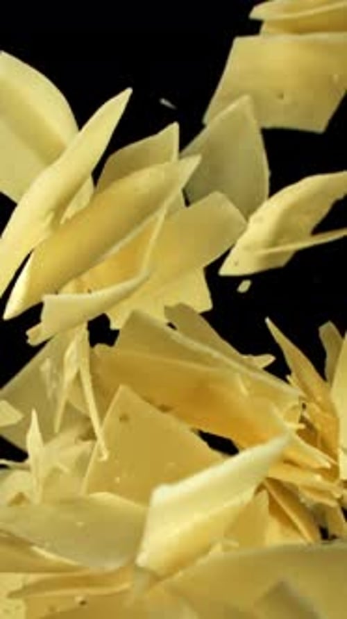 Parmesan Cheese Flakes Fly Upwards on a Black Background Filmed on a Highspeed Camera at 1000 Fps