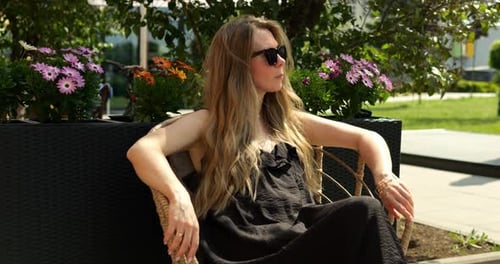 Femme allongée sur une chaise avec les bras posés sur les côtés avec une expression sereine