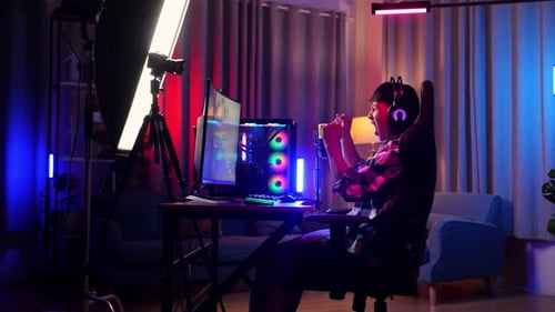 Side View Of Asian Boy Streamer Celebrating Winning Game On Personal Computer