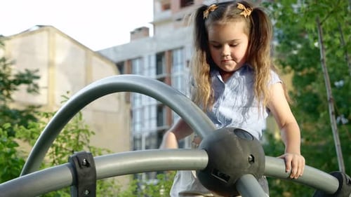 Young Girl Climbing on Playground Equipment in Urban Park During Sunny Afternoon