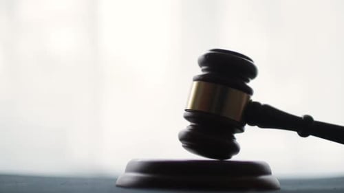 Wooden Gavel Tapping Against Block in Court