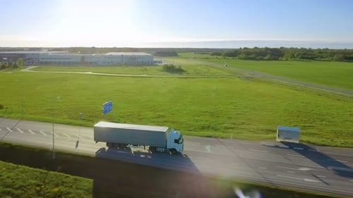 Aerial View of White Semi Truck with Cargo Trailer Driving on the Highway. In the Background Wareho