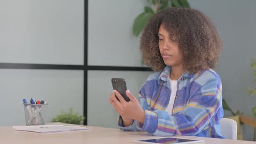 Young Woman Using Smartphone at Desk Indoors
