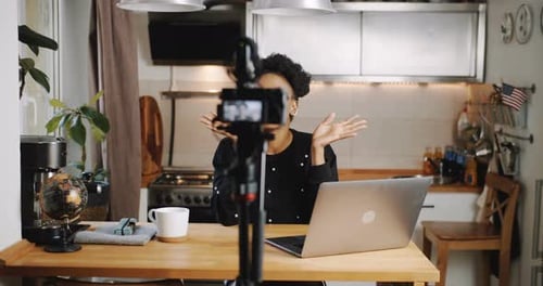 Woman Vlogging in Kitchen with Laptop and Camera
