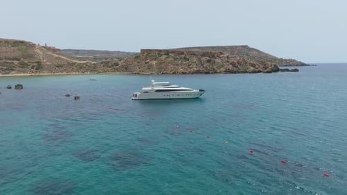 Yacht Floating In The Blue Sea By Riviera Beach In Qarraba Bay, Mġarr, Malta. - aerial shot