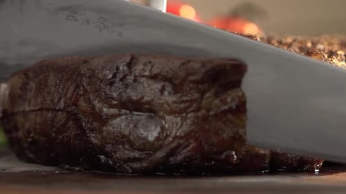 Extreme close up shot on piece of steak cutting using a kitchen knife and barbecue fork. Perfectly c