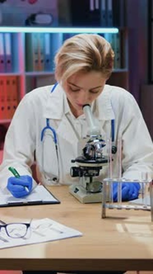 Focused Woman Using Microscope in a Science Lab