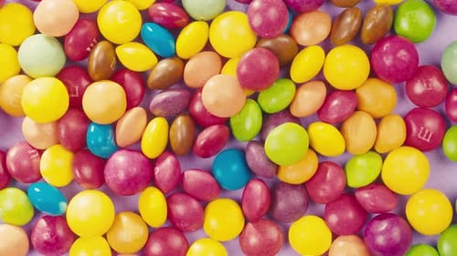 Colorful Dragee Candies with Glitter Sprinkles on Purple Background Summer Bright Texture Studio