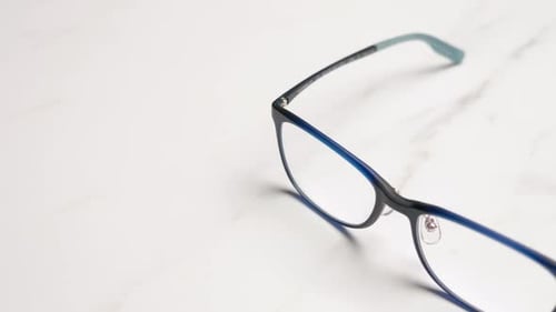 Panning on a close-up of a pair of eyeglasses placed on top of a table.