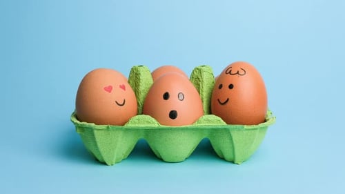 Cute Easter Eggs with Funny Faces in Green Box Isolated on Blue Background