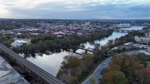 Drone shot of intersection with cars and river with bridge and dam in autumn. American small town in