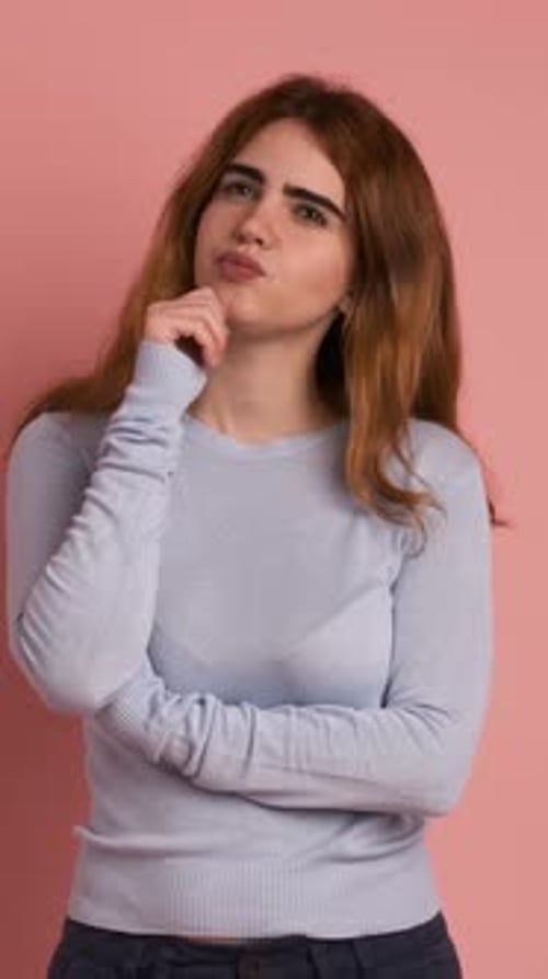 Woman Thinking, Smiling in front of Pink Backdrop